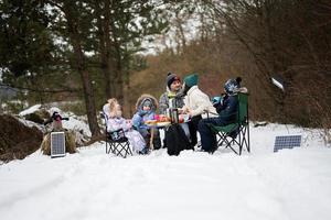 Family with three children in winter forest spending time together on a picnic. photo