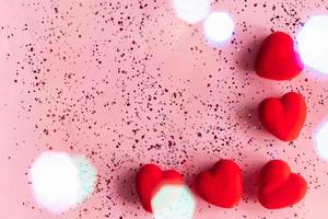 Frame of red hearts on a pink background with confetti. Valentine's Day template with copy space photo