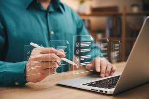 Quick checklist and clipboard management concept, businessman working checklist questionnaire assessment form, checking laptop performance and filling out online survey, efficient management. photo