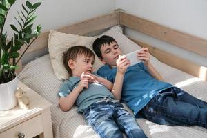 Two little brothers happily watching cartoons together on a smartphone. Children and gadget concept photo