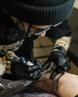 Professional tattoo artist stuffs a tattoo on the man's hand. Tattoo artist at work. Tattoo creation process. Art and creativity photo
