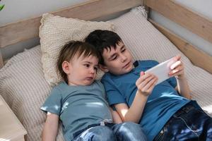 Two little brothers happily watching cartoons together on a smartphone. Children and gadget concept photo