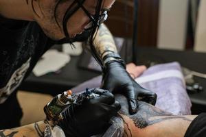 Professional tattoo artist stuffs a tattoo on the man's hand. Tattoo artist at work. Tattoo creation process. Art and creativity photo