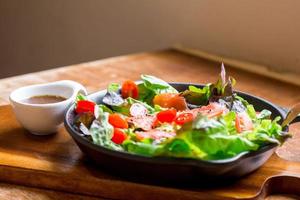 Smoke salmon Salad with green and red oak and cherry tomato served with sesame salad dressing. Homemade food. The concept for a tasty and healthy meal. photo