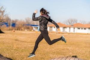 joven hembra corredor es saltando terminado de madera obstáculos en campo foto