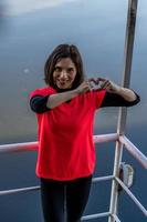 linda joven mujer demostración corazón firmar con manos en un barco foto