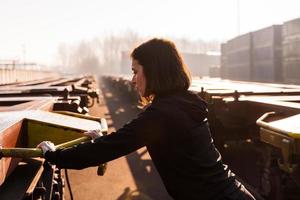 young female runner takes a break on a freight train in the commercial port in the morning photo