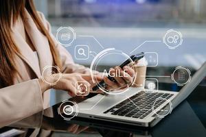 ágil desarrollo metodología concepto. negocio mano utilizando ordenador portátil y tableta con virtual pantalla ágil icono en moderno oficina digital tecnología concepto. foto