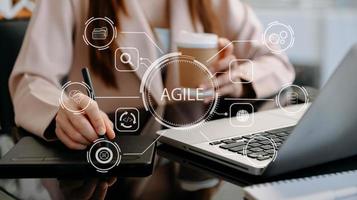 ágil desarrollo metodología concepto. negocio mano utilizando ordenador portátil y tableta con virtual pantalla ágil icono en moderno oficina digital tecnología concepto. foto