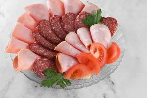 plate with an assortment of boiled, smoked sausage on bright table. photo