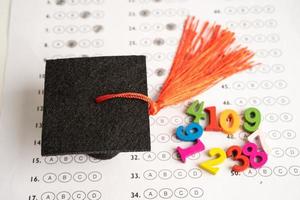 sombrero de brecha de graduación y lápiz en el fondo de la hoja de respuestas, concepto de enseñanza de aprendizaje de prueba de estudio de educación. foto