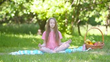 weinig meisje in yoga positie in de park. video