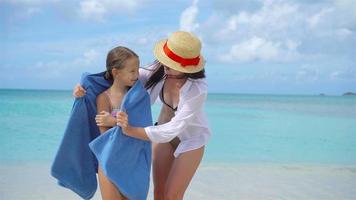 Mom wraps a small daughter with a towel after swimming in the sea. Mother and little daughter enjoying time at tropical beach video