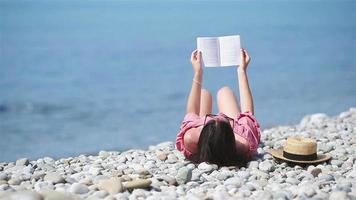 Young woman reading book during tropical white beach video