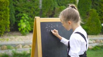 glückliches kleines Schulmädchen mit einer Tafel im Freien video