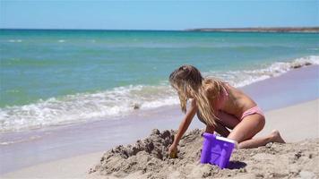 menina na praia branca tropical fazendo castelo de areia video