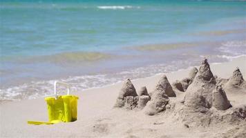 Sandcastle at white tropical beach with plastic kids toys video