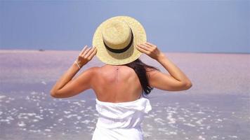mujer con sombrero camina sobre un lago salado rosa en un día soleado de verano. video