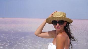 Woman in hat walk on a pink salt lake on a sunny summer day. video