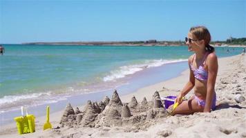 petite fille à la plage blanche tropicale faisant un château de sable video