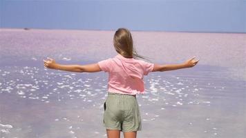 fille sur un lac salé rose par une journée d'été ensoleillée. video