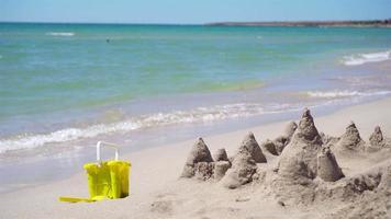 Sandburg am weißen tropischen Strand mit Plastikspielzeug für Kinder video