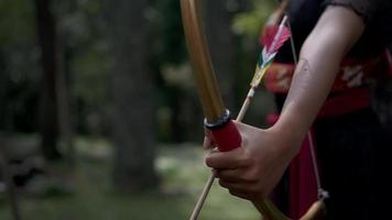 Close up shot of woman hand ready to shoot an arrow from a gold bow video