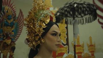 una glamurosa mujer balinesa con un traje dorado mientras está de pie entre la puerta balinesa video