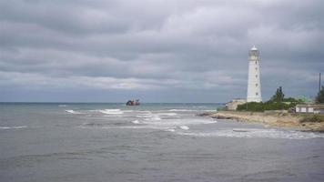 Seascape with beautiful white lighthouse against stormy sk and sea video