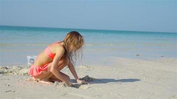 adorável menina brincando com brinquedos de praia na praia tropical branca video