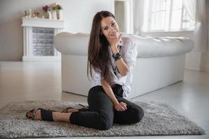 Lovely young woman sitting by the sofa photo