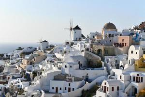 Charming view Oia village on Santorini island, Greece. Traditional famous blue dome church over the Caldera in Aegean sea. Traditional blue and white Cyclades architecture. photo