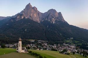 S t. valentin castelruth pueblo Iglesia en el verano en el dolomita Alpes. increíble paisaje con pequeño capilla en soleado prado y mascotas pico a castelruth comuna. dolomitas, sur Tirol, Italia foto