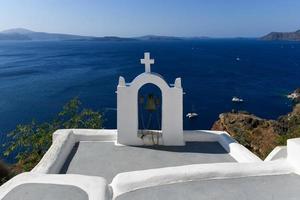 Charming view Oia village on Santorini island, Greece. Traditional famous blue dome church over the Caldera in Aegean sea. Traditional blue and white Cyclades architecture. photo