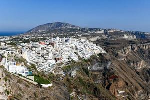 Charming view Fira village on Santorini island, Greece. Traditional famous blue dome church over the Caldera in Aegean sea. Traditional blue and white Cyclades architecture. photo