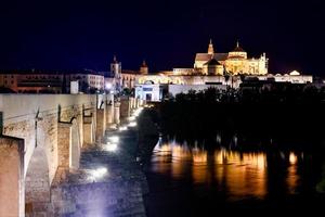 View of the Roman Bridge, a stone bridge that spans the river Guadalquivir in Cordoba, Spain at night. photo