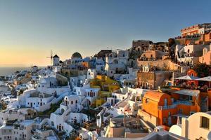 Oia, Greece - Jul 22, 2021, Classic Oia, Santorini skyline at sunset with buildings in Greece. photo