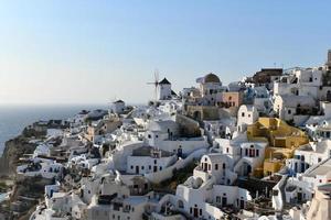 Charming view Oia village on Santorini island, Greece. Traditional famous blue dome church over the Caldera in Aegean sea. Traditional blue and white Cyclades architecture. photo