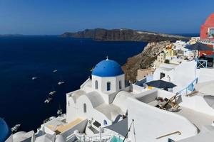 Charming view Oia village on Santorini island, Greece. Traditional famous blue dome church over the Caldera in Aegean sea. Traditional blue and white Cyclades architecture. photo