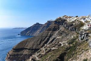 Charming view Fira village on Santorini island, Greece. Traditional famous blue dome church over the Caldera in Aegean sea. Traditional blue and white Cyclades architecture. photo