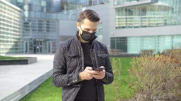 Man wearing a mask on a background of a modern building, video