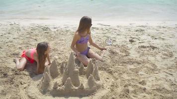 Zwei kleine glückliche Mädchen haben viel Spaß am tropischen Strand und spielen zusammen video