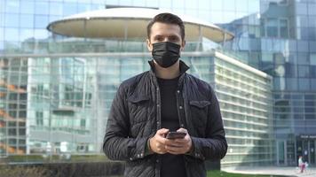 Mens vervelend een masker Aan een achtergrond van een modern gebouw, video