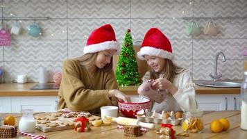 Kleine Mädchen machen Weihnachtslebkuchenhaus am Kamin im dekorierten Wohnzimmer. video