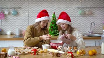 Kleine Mädchen machen Weihnachtslebkuchenhaus am Kamin im dekorierten Wohnzimmer. video