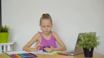 grave scolara seduta a tavolo con il computer portatile e manuale e fare compiti a casa. video