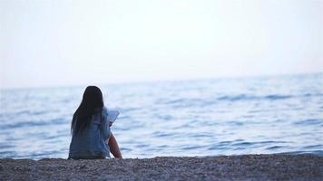 mujer joven leyendo en la playa blanca tropical video