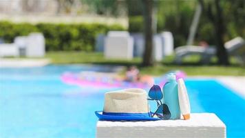 Suncream, hat, sunglasses near swimming pool video