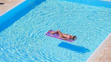 mujer joven en bikini colchón de aire en la gran piscina video