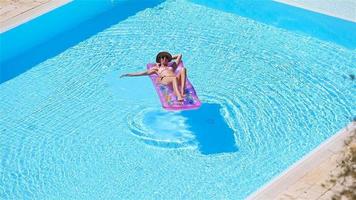 mujer joven en bikini colchón de aire en la gran piscina video